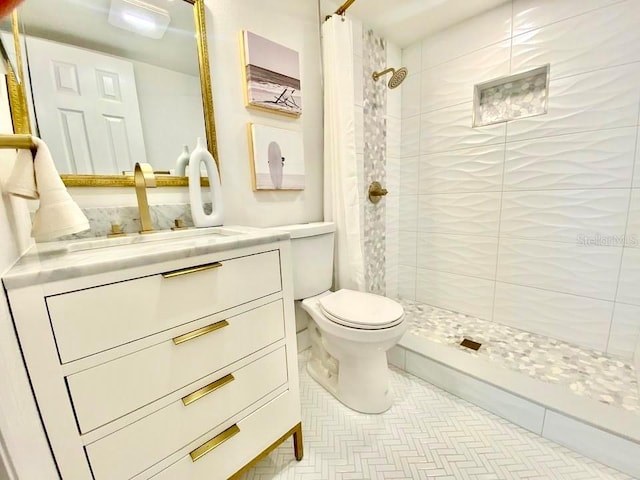 bathroom with tile floors, a tile shower, toilet, and vanity