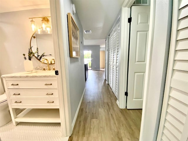 hall with light hardwood / wood-style floors and sink