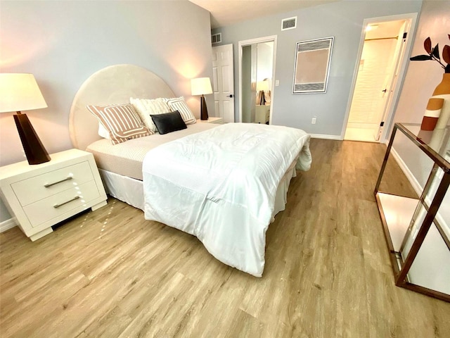 bedroom featuring light hardwood / wood-style floors and ensuite bath