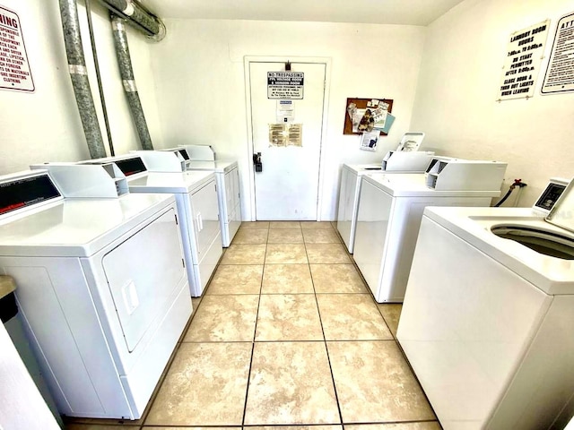 clothes washing area with light tile flooring and washing machine and dryer