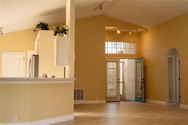 foyer with light tile patterned floors and high vaulted ceiling