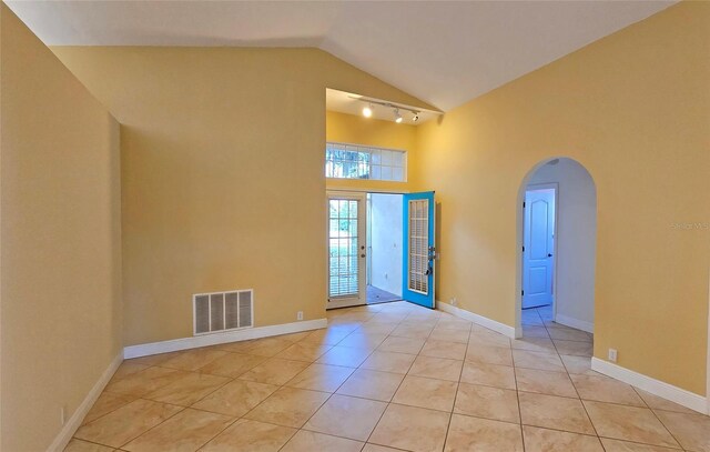 unfurnished room featuring light tile patterned flooring and vaulted ceiling