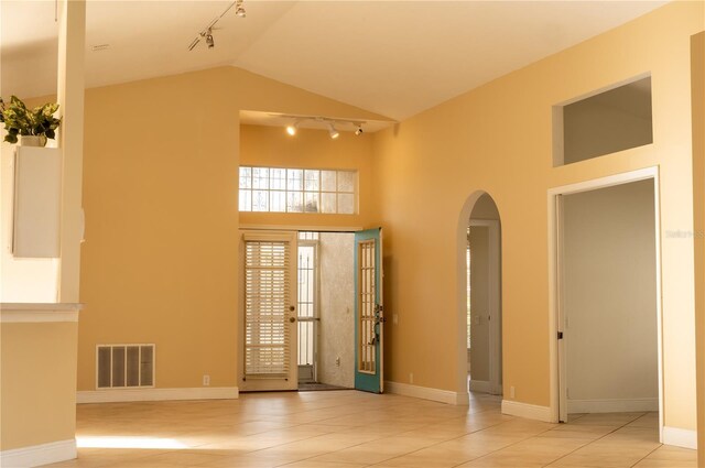 tiled empty room featuring french doors and high vaulted ceiling