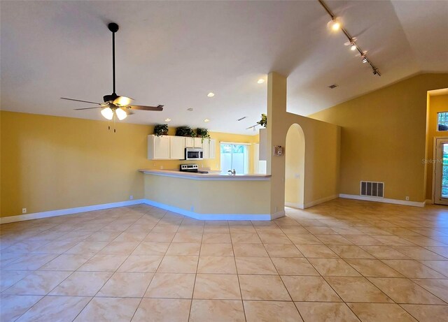 kitchen with kitchen peninsula, light tile patterned floors, white cabinetry, and lofted ceiling