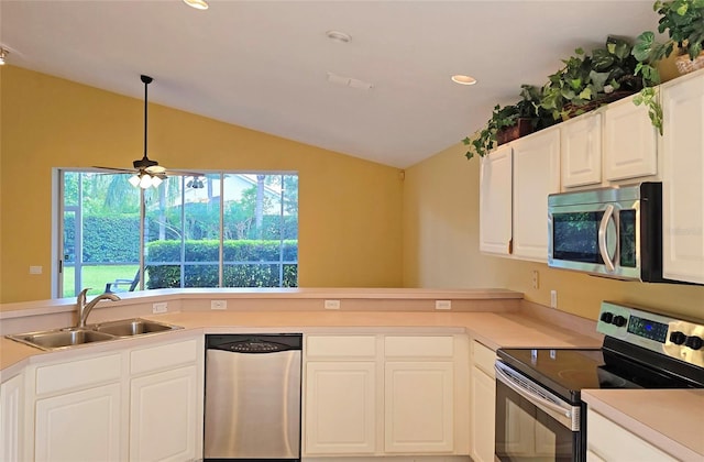 kitchen with sink, vaulted ceiling, appliances with stainless steel finishes, decorative light fixtures, and white cabinetry