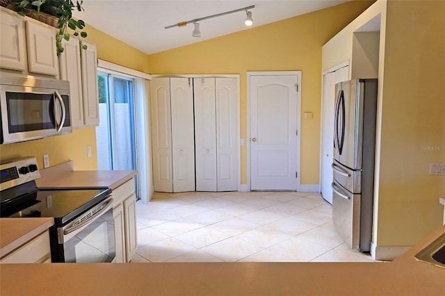 kitchen featuring light tile patterned floors, stainless steel appliances, and lofted ceiling