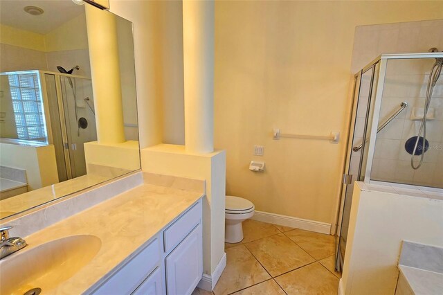 bathroom with tile patterned floors, vanity, a shower with shower door, and toilet