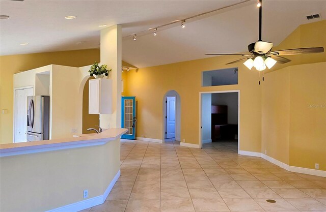 kitchen with ceiling fan, rail lighting, stainless steel fridge, lofted ceiling, and light tile patterned floors