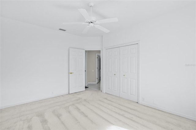 unfurnished bedroom featuring ceiling fan, a closet, and light colored carpet