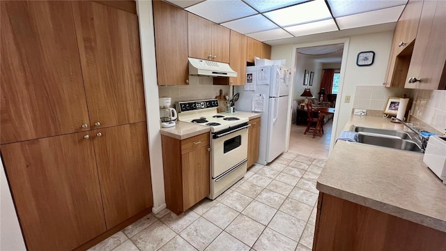 kitchen featuring white appliances, sink, tasteful backsplash, and light tile flooring