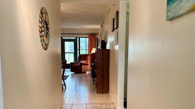 corridor featuring a textured ceiling and light tile floors