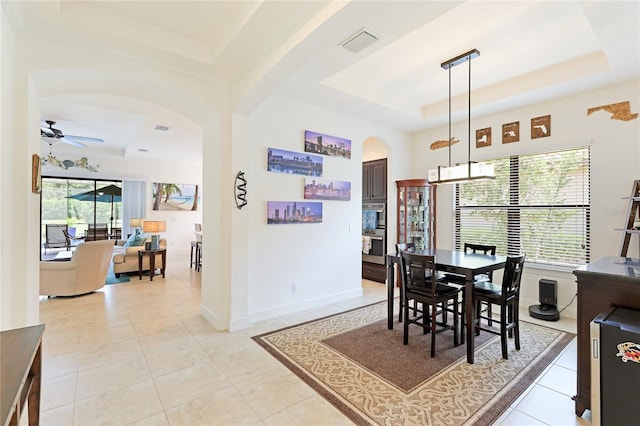 dining room featuring a tray ceiling, ceiling fan, plenty of natural light, and light tile patterned floors