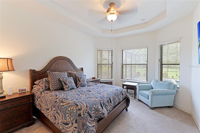 bedroom with a tray ceiling, ceiling fan, and light carpet