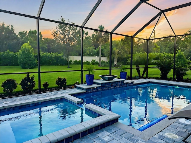 pool at dusk featuring a lanai and a yard