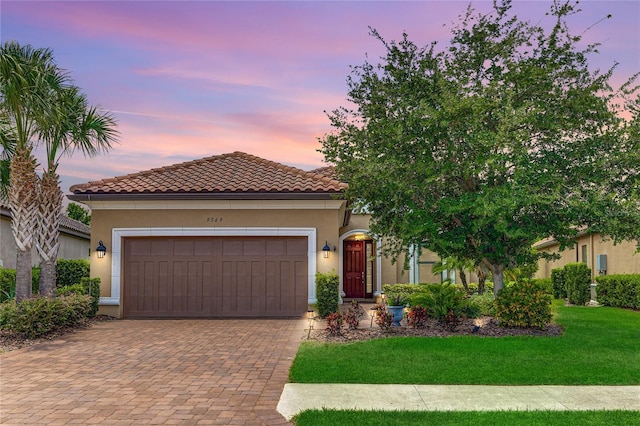 mediterranean / spanish-style home featuring a garage and a yard