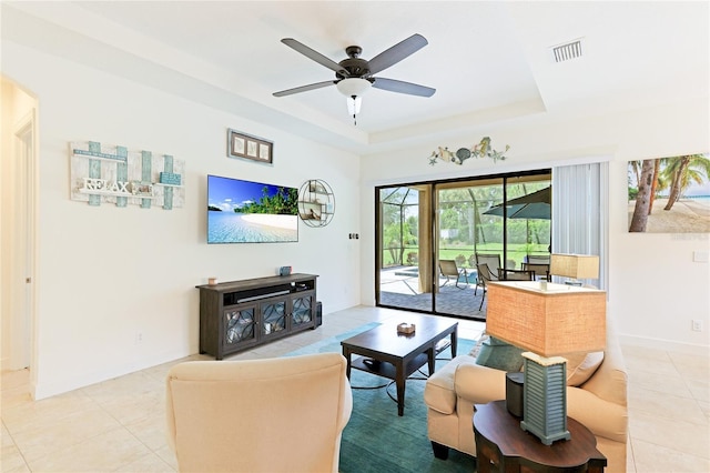 tiled living room with a raised ceiling and ceiling fan