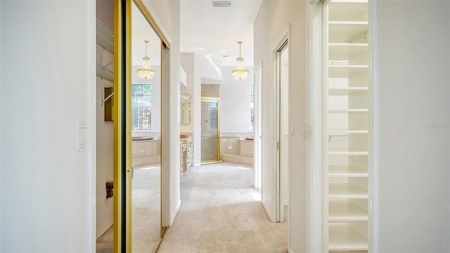 hallway with a notable chandelier and light colored carpet