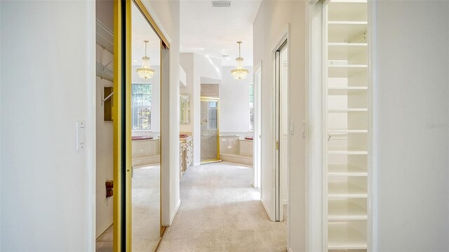 7430 Weeping Willow Dr, Sarasota, FL 34241 - hallway with light colored carpet and a notable chandelier