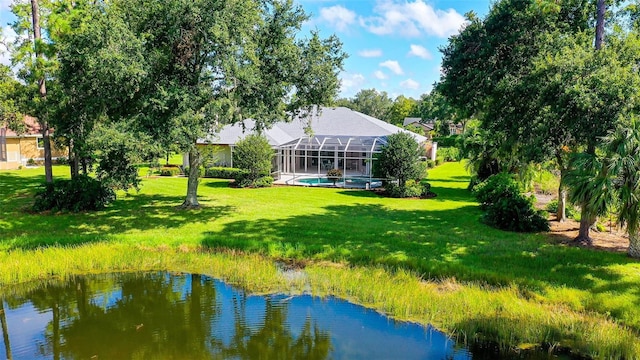 rear view of property featuring glass enclosure, a yard, and a water view