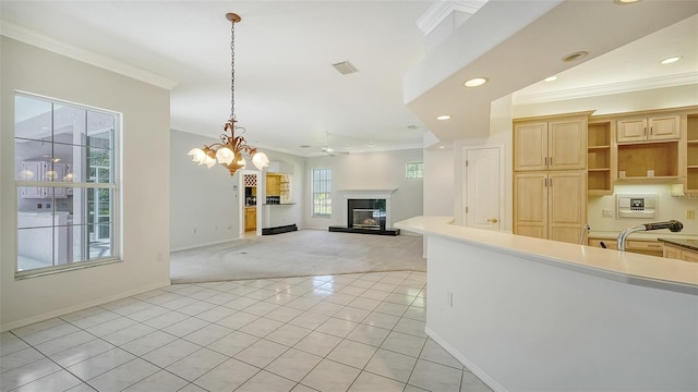 kitchen with decorative light fixtures, light carpet, ornamental molding, ceiling fan with notable chandelier, and light brown cabinetry