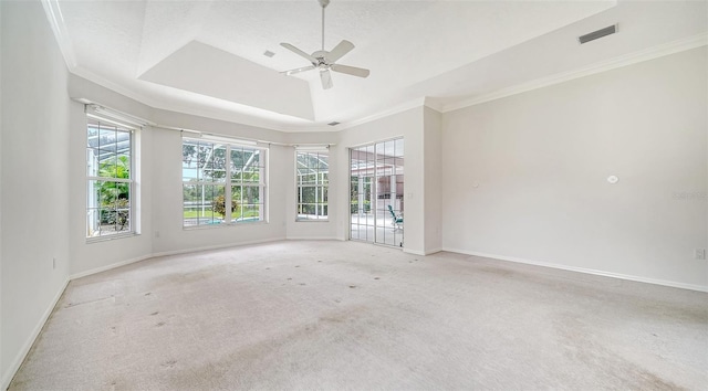 empty room featuring ornamental molding, a raised ceiling, ceiling fan, and light carpet