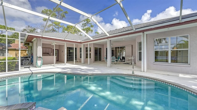 view of pool with ceiling fan, glass enclosure, and a patio