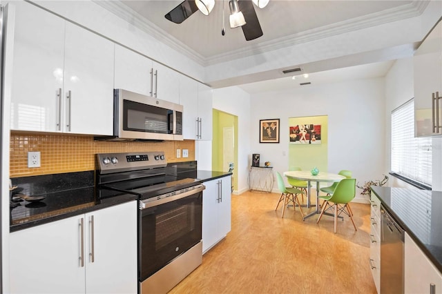 kitchen with backsplash, white cabinets, ceiling fan, ornamental molding, and appliances with stainless steel finishes