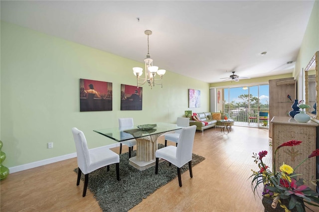 dining area with ceiling fan with notable chandelier and light hardwood / wood-style floors