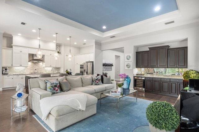 living room featuring a tray ceiling, wine cooler, and dark wood-type flooring