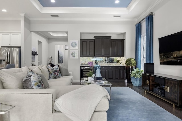 living room featuring dark hardwood / wood-style flooring, a raised ceiling, and crown molding