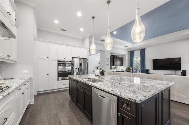 kitchen featuring stainless steel appliances, sink, pendant lighting, white cabinets, and an island with sink