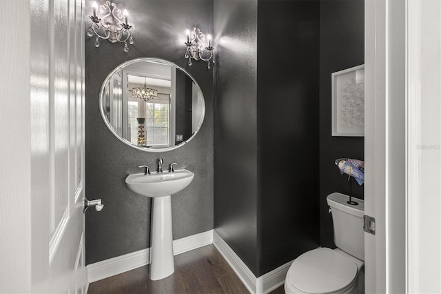 bathroom featuring hardwood / wood-style floors, toilet, and an inviting chandelier