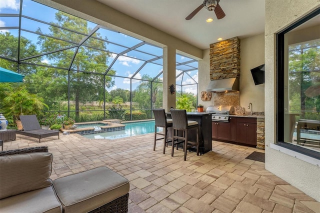 view of patio featuring area for grilling, ceiling fan, exterior kitchen, a swimming pool with hot tub, and glass enclosure