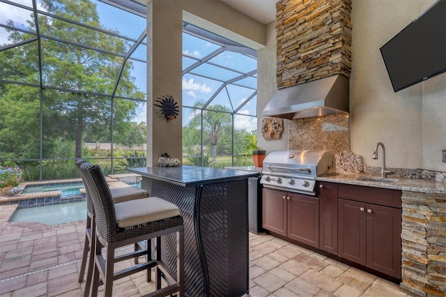 view of patio featuring glass enclosure, sink, exterior kitchen, a grill, and an in ground hot tub