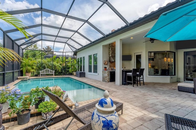 view of swimming pool featuring a bar, a lanai, ceiling fan, and a patio area