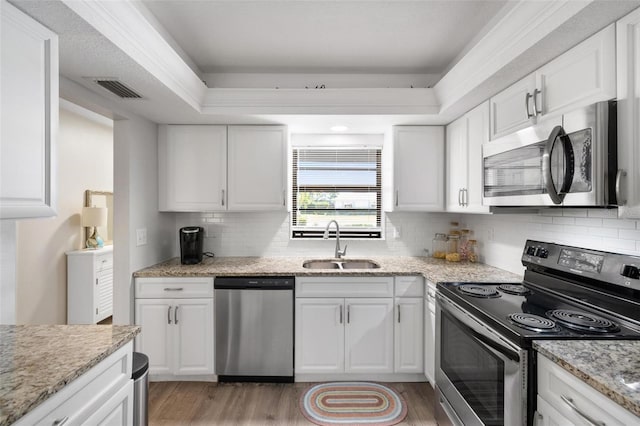 kitchen featuring white cabinetry, sink, stainless steel appliances, tasteful backsplash, and light stone counters