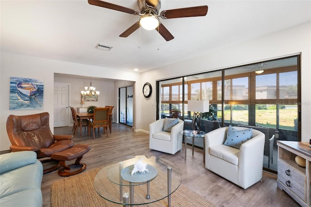 living room with hardwood / wood-style floors and ceiling fan with notable chandelier