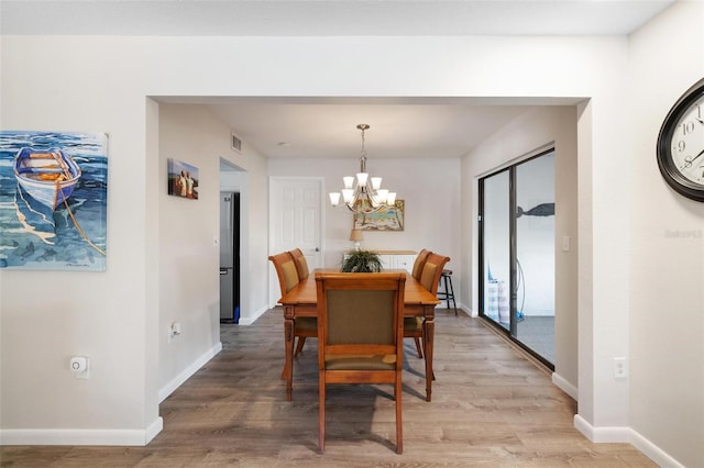 dining area with hardwood / wood-style floors and an inviting chandelier