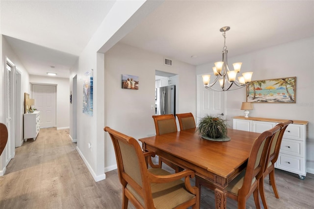 dining area featuring light hardwood / wood-style floors and a notable chandelier