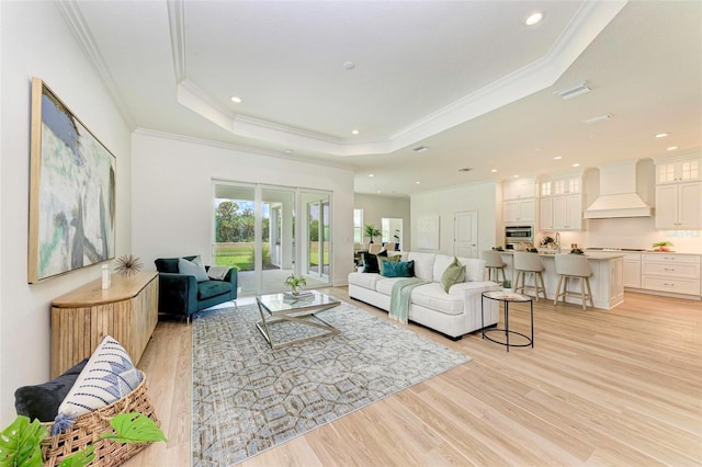 living room with crown molding, a raised ceiling, and light hardwood / wood-style flooring