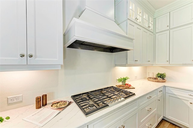 kitchen featuring custom exhaust hood, light stone countertops, white cabinets, and stainless steel gas stovetop