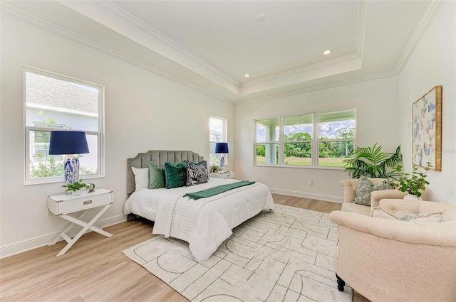 bedroom with crown molding, light wood-type flooring, and a tray ceiling