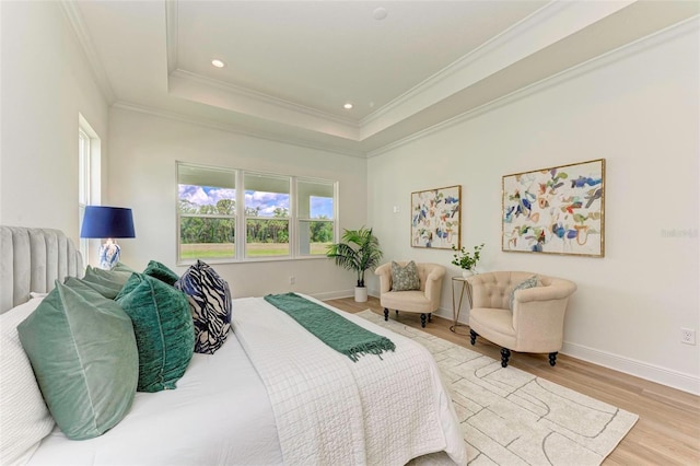 bedroom with a tray ceiling, light hardwood / wood-style flooring, and ornamental molding