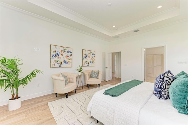 bedroom featuring ornamental molding, a raised ceiling, and light wood-type flooring