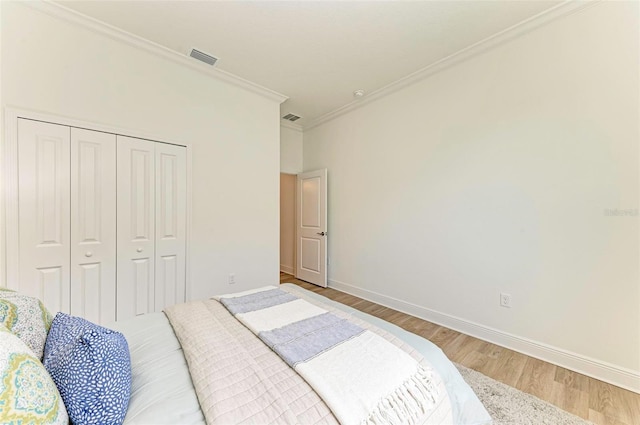 bedroom with hardwood / wood-style floors, crown molding, and a closet