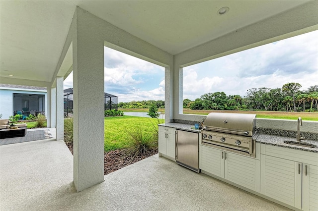 view of patio featuring an outdoor kitchen, a grill, sink, a lanai, and a water view