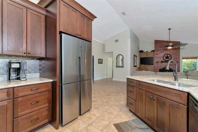 kitchen with vaulted ceiling, appliances with stainless steel finishes, light stone counters, sink, and tasteful backsplash