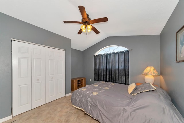 bedroom with lofted ceiling, ceiling fan, light tile patterned floors, and a closet