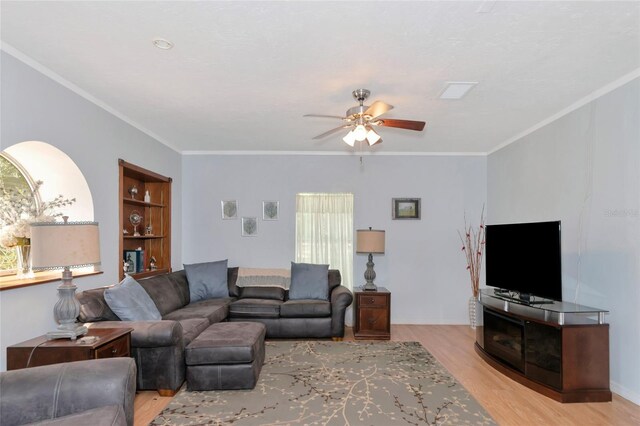 living room with built in shelves, ornamental molding, light hardwood / wood-style floors, and ceiling fan