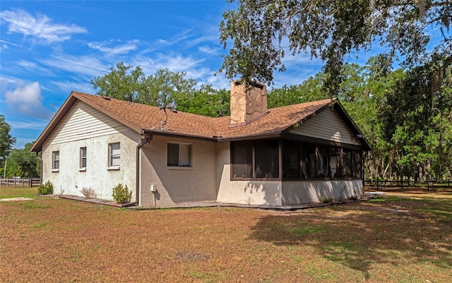 back of property featuring a yard and a sunroom